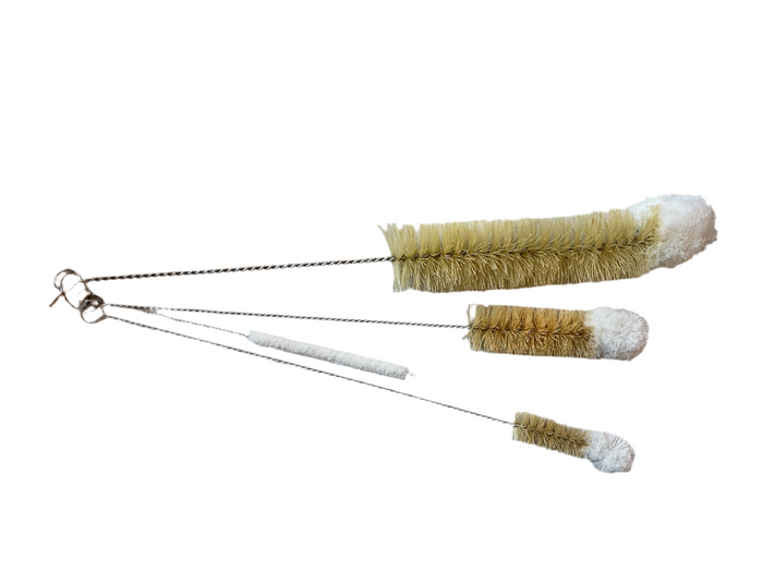 A set of bottle brushes with wooden handles and beige bristles, laid out on a white surface.