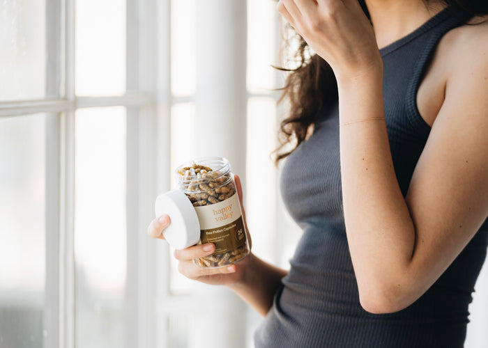 Close-up of Happy Valley Honey Bee Pollen Capsules 300, showing the smooth, golden capsules in a clear container.