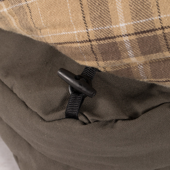 Close-up of plaid fabric, button, and olive green material on a stylish outdoor cushion.