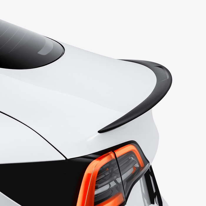 Close-up of the HALOBLK Store Carbon Fiber Rear Spoiler installed on a Tesla Model 3, highlighting its sleek black finish and modern LED taillights with orange accents, set against a plain white background.