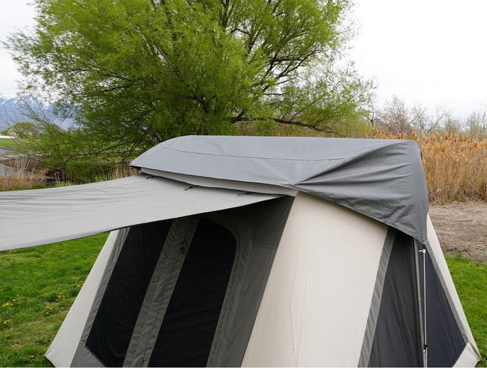 Gray camping tent with extended rainfly in outdoor setting, featuring durable fabric and spacious design.