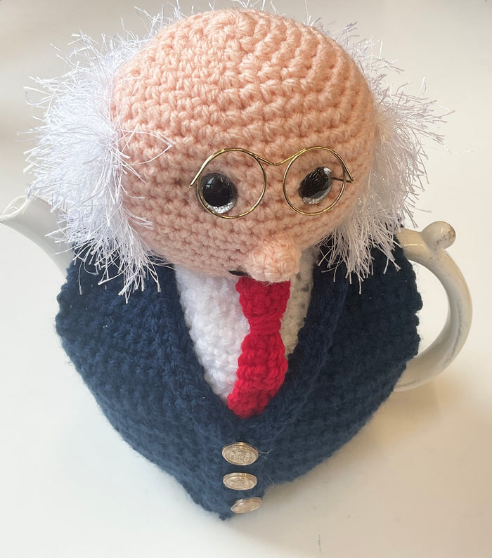 Crocheted tea cozy with a face design on a white background