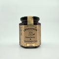 A jar of Crossogue Strawberry & Champagne Jam with a label that includes the product name and information about the product being hand made in small batches.