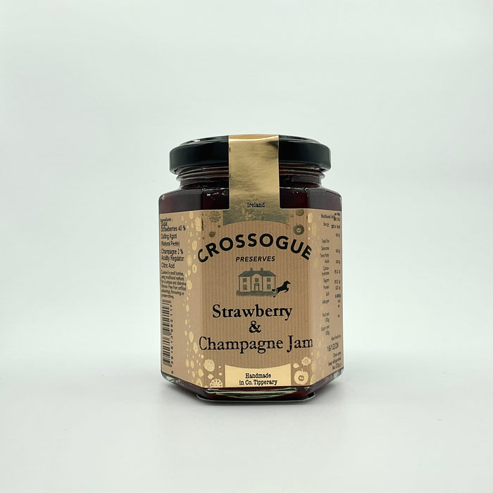 A jar of Crossogue Strawberry & Champagne Jam with a label that includes the product name and information about the product being hand made in small batches.