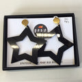 A pair of large black star-shaped earrings with gold studs, presented in a box with a brand tag.