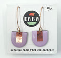 A pair of purple earrings with metallic details, labeled 'DANA' on a card that reads 'UPCYCLED FROM YOUR OLD RECORDS!'.