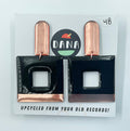 A pair of Dana Jewellery Mika earrings in black and copper, displayed on a card indicating they are upcycled from old records.