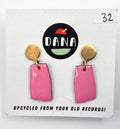 A pair of pink earrings with metallic details, displayed on a card with the Dana Jewellery brand logo and text 'UPCYCLED FROM YOUR OLD RECORDS!'.