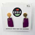 A pair of purple earrings with metallic details, labeled 'DANA' on a card that reads 'UPCYCLED FROM YOUR OLD RECORDS!'
