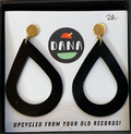 A pair of black teardrop-shaped earrings with gold-colored hoop earrings, displayed in a case with a 'Dana' brand mark and a tagline that reads 'UPCYCLED FROM YOUR OLD RECORDS!'.