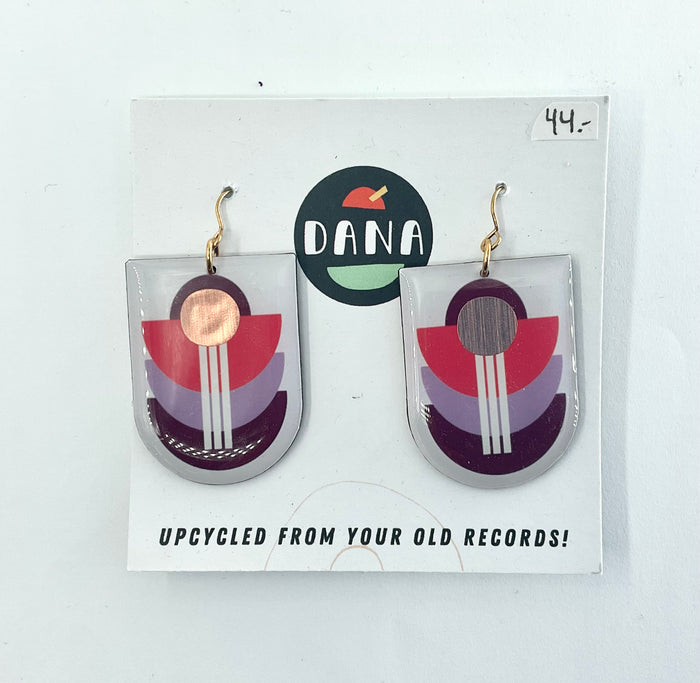 A pair of bronze multicolored earrings made from upcycled vinyl records, displayed on a white card with the brand name 'dana' at the top.