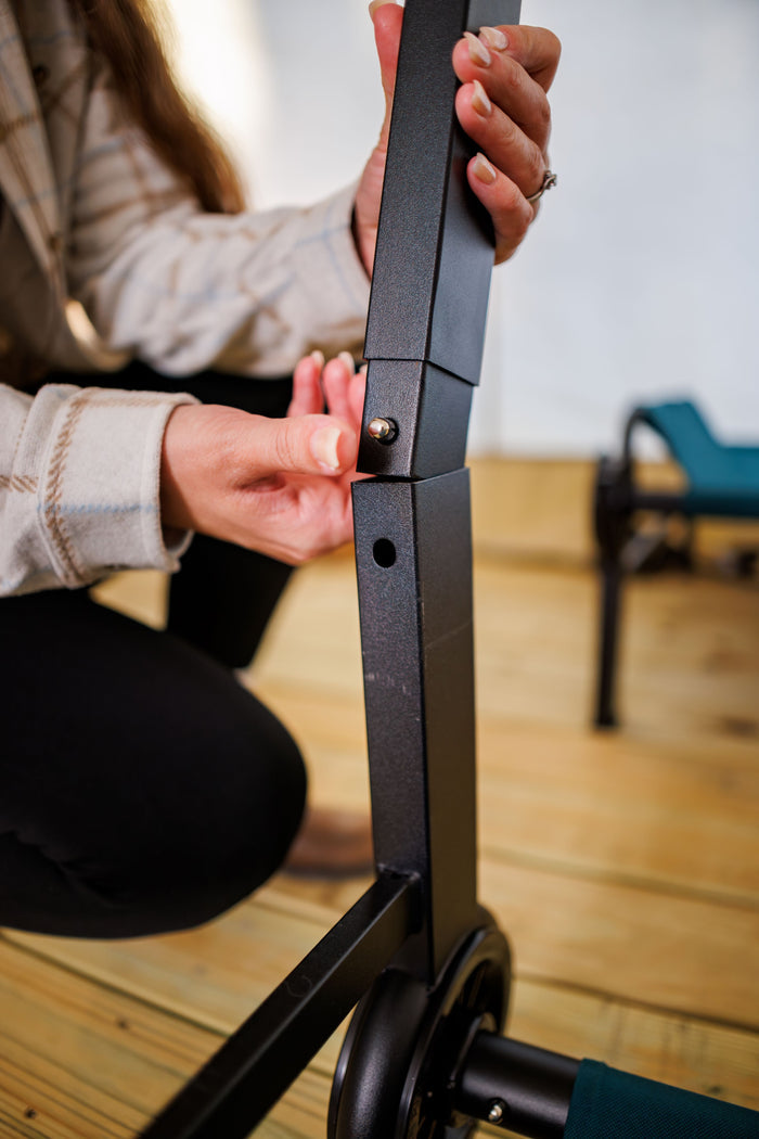 Close-up of a black metal chair frame with a person adjusting the armrest.