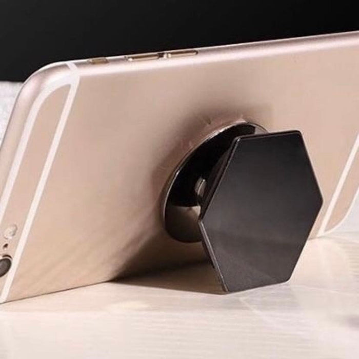 Silver expanding finger grip by 9eight5 for phones and tablets, shown attached to a device with office and vehicle background.