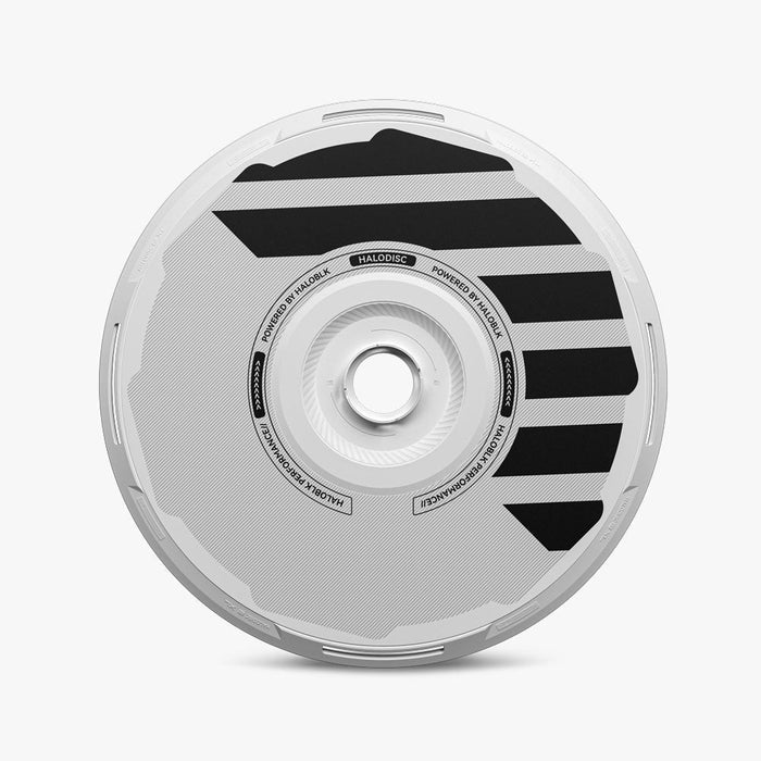 A round, silver HALODISC 2 Replacement Wheel Cover for Tesla Model Y by HALOBLK Store, viewed from the side with bold black diagonal stripes, subtle textured patterns, a central hub, and lettering along the inner circle.