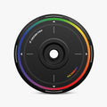 A round, black HALODISC 2 Replacement Wheel Cover by HALOBLK Store for Tesla Model Y features a central hole, white markings, and a rainbow-colored border; “HALO DISC 2” and “RAINBOW” are printed on the surface.
