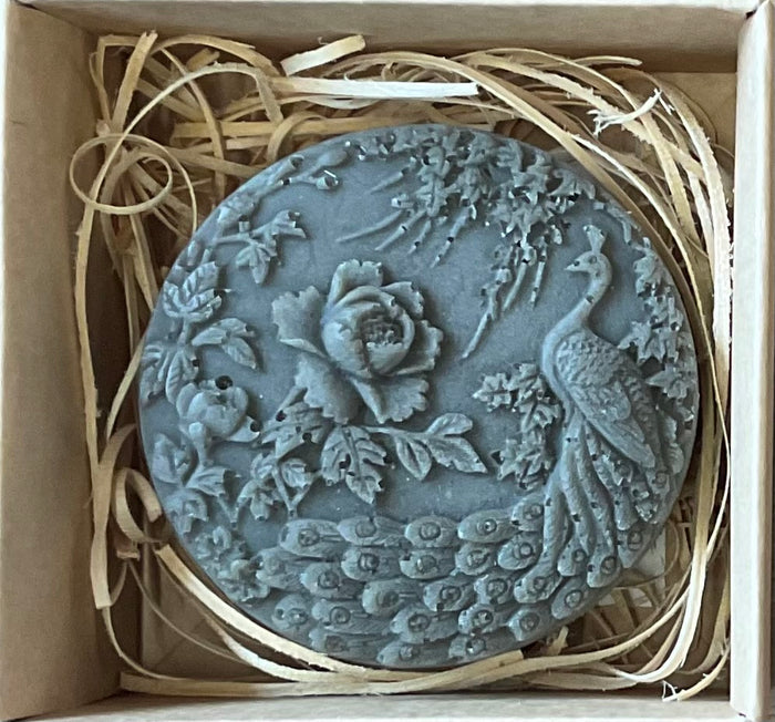 Decorative stone with peacock and floral design in a box with straw