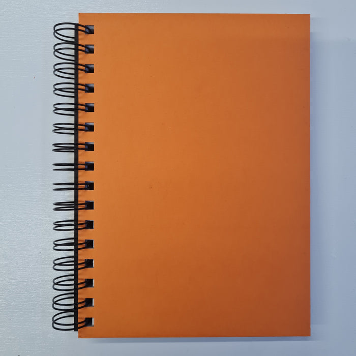 An orange hardcover notebook with a wire binding and plain, dotted pages.