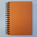 An orange hardcover notebook with a wire binding and plain, dotted pages.