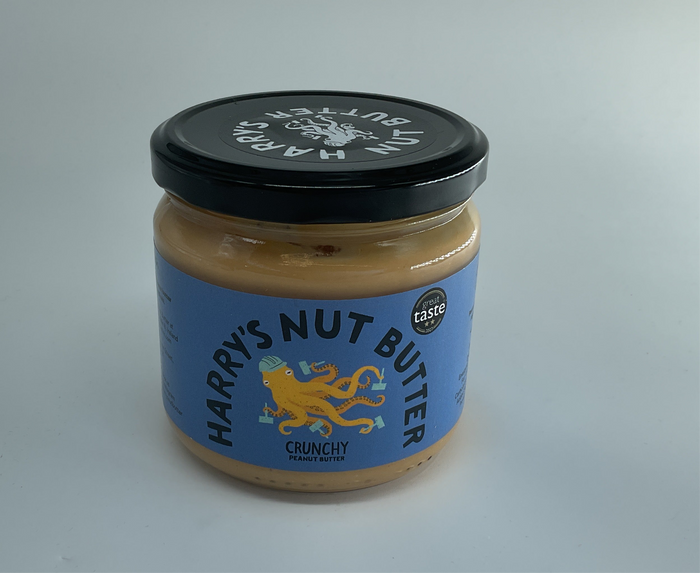 Jar of Harry's Nut Butter with a black lid on a gray background