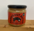 Jar of Harry's Nut Butter with a red label featuring a cat illustration on a wooden surface.