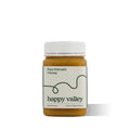 Jar of Happy Valley Honey Kamahi Gourmet & Raw Honey with golden color and honey dipper, showcasing natural and pure honey.