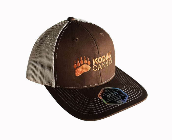 Brown trucker hat with mesh back, Kodiak Canvas logo and bear paw embroidery, perfect for outdoor enthusiasts.
