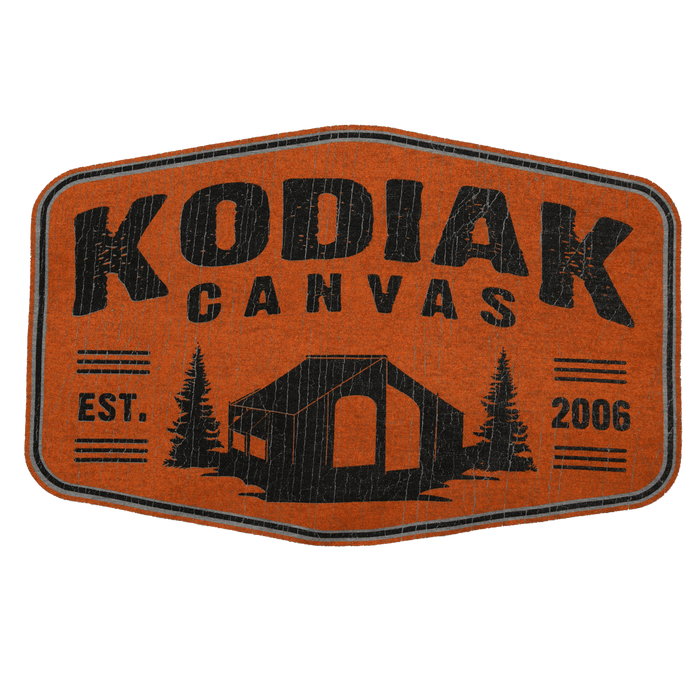 Kodiak Canvas logo patch in orange, featuring a tent and pine trees, established in 2006.