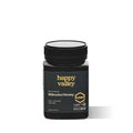 Jar of Happy Valley Honey Manuka Honey UMF® 15+ with golden honey inside on a wooden surface