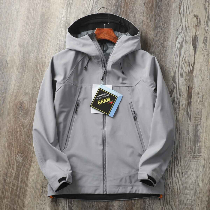 Men's waterproof softshell jacket by Mead's Supply & Equipment Outfitters, windproof hooded hiking shell, shown in black outdoor setting.