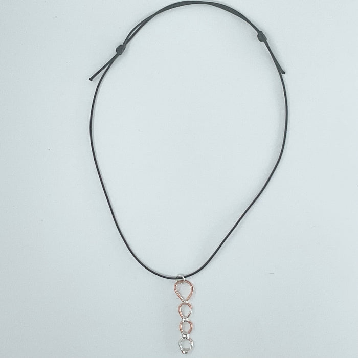 A black adjustable cord necklace featuring a dangling pendant with a rose gold teardrop frame and three silver-toned oval links at the bottom, displayed on a light gray background.
