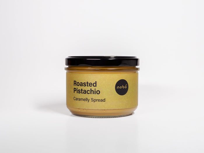 Jar of roasted pistachio caramelly spread on a white background