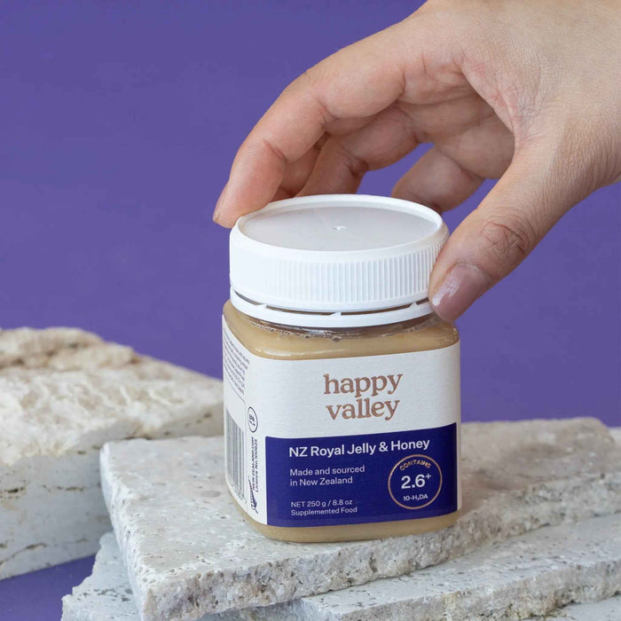 Jar of Happy Valley Honey Royal Jelly with honeycomb and honey drizzles, showcasing fresh royal jelly and honey in a glass jar.
