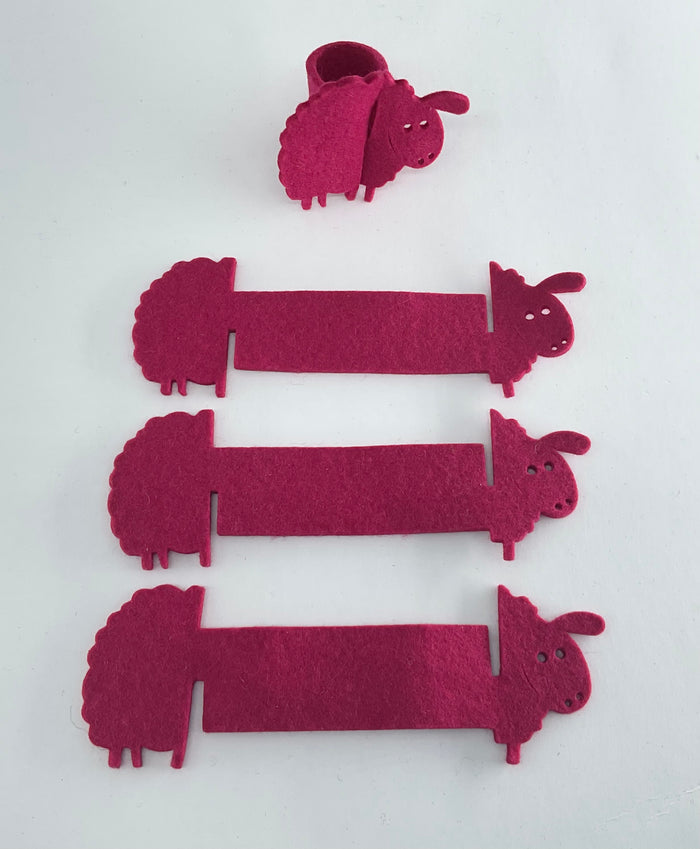 Set of pink sheep-shaped napkin holders on a white background