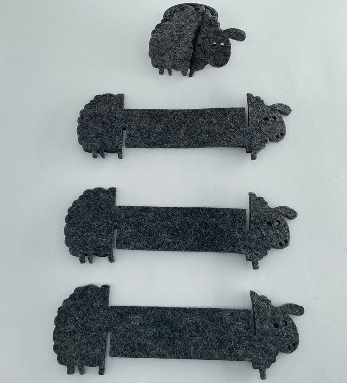 Set of black sheep-shaped napkin holders on a white background