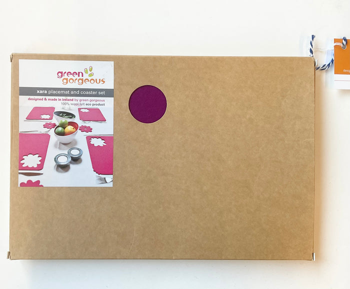 Brown box with a window displaying pink placemats and coasters, branded 'Green Gorgeous'.