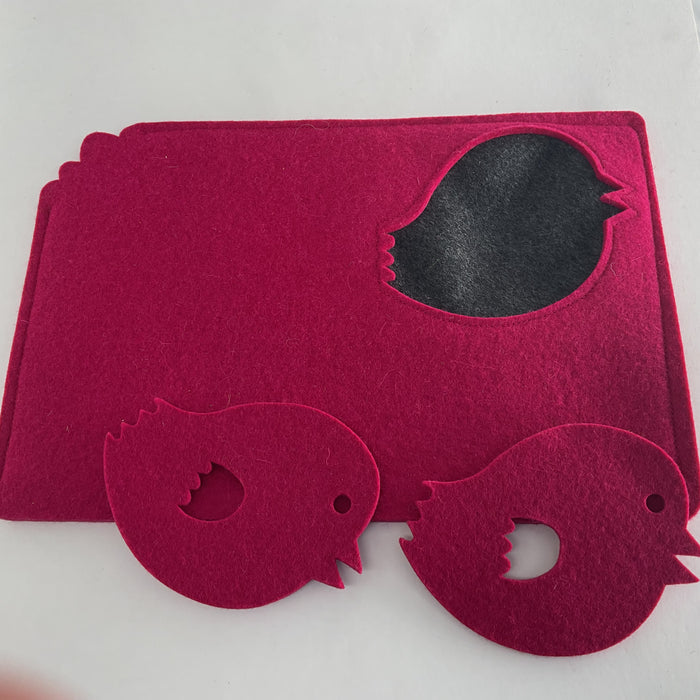 Pink felt tea cosy with cut-out shapes on a white background with also pink bird felt coasters