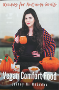 A book cover for 'Recipes for Autumn Souls' featuring a woman holding a mug with a colorful blanket in the background, and various kitchen items like pumpkins and a teapot.