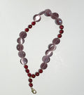 Beaded necklace with purple and red beads on a white background