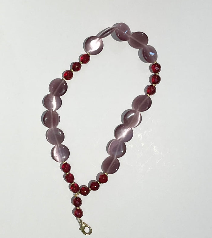 Beaded necklace with purple and red beads on a white background