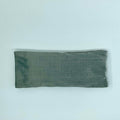 A gray silk eye mask laid flat on a white background.