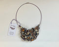 Necklace with intricate design and tag on a light background