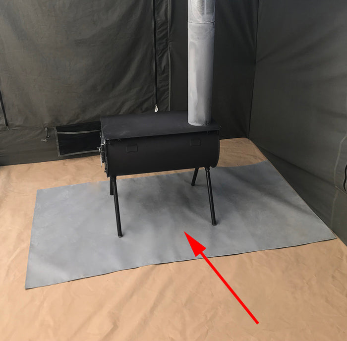 Black outdoor camping wood stove with chimney pipe, set up in a tent on a gray heat-resistant mat.