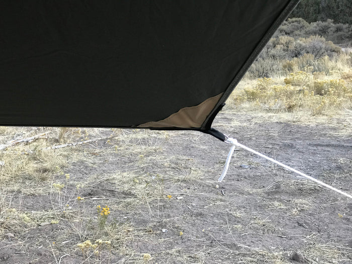 Black camping tarp with reinforced edges and guy lines, ideal for outdoor shelter and protection.