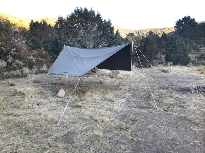 Durable gray camping tarp with black side, perfect for outdoor shelter and weather protection.