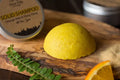 Yellow solid shampoo bar on a wooden board with a metal container labeled 'Solid Shampoo' in the background.