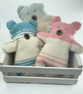 Three teddy bears with striped patterns in a white crate on a light gray background
