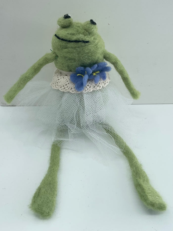 Frog toy in a white dress with a blue flower on a white background