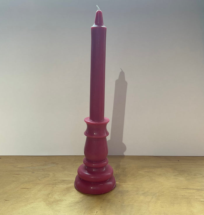 Purple candle on a wooden surface with a plain background