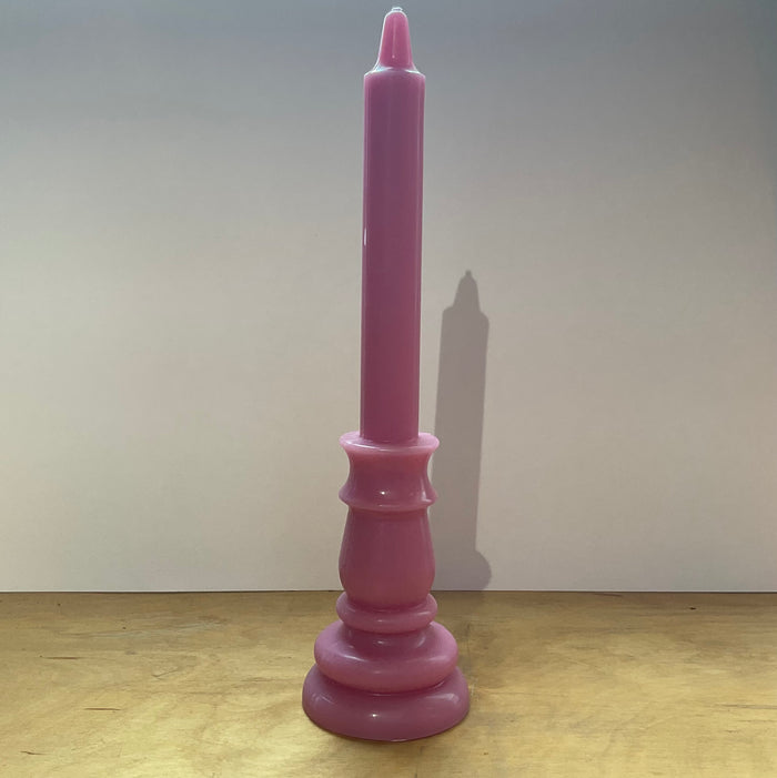 Pink candle on a pink candlestick against a white background