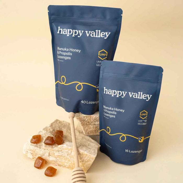 Two packs of Happy Valley Honey UMF 10+ Manuka Honey & Propolis Lemon Lozenges with lemon slices and lozenge packs.